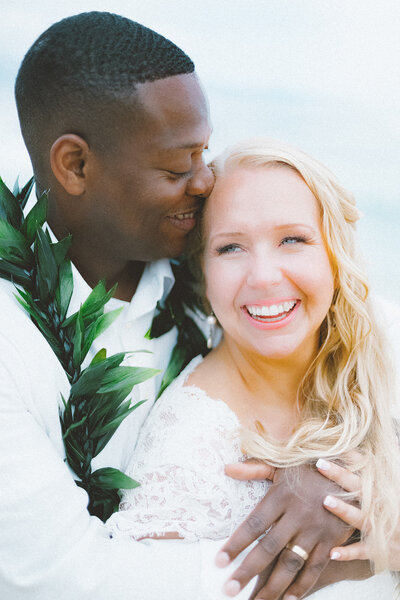 black groom and white bride cuddle and laugh in an embrace 