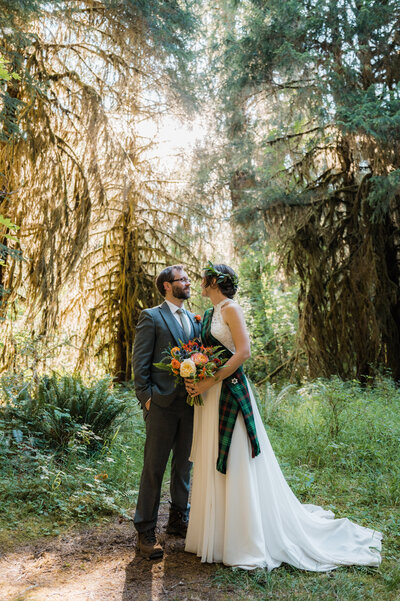 Bride and groom posing for photos during their elopement day at the Hoh Rainforest in Olympic National Park