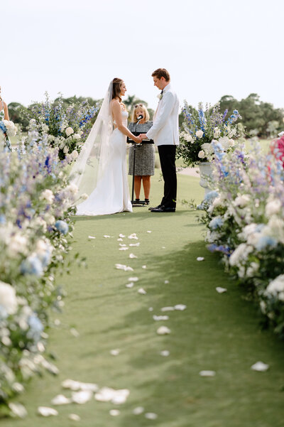 Bride and groom kissing under beautiful green tree in the summer right before they meet their family for their wedding ceremony - by Daniella Diaz Photo