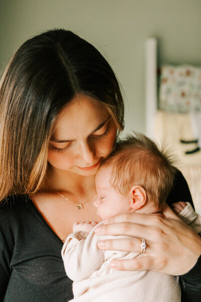 A mom snuggles her newborn baby in the nursery at a newborn session in their home