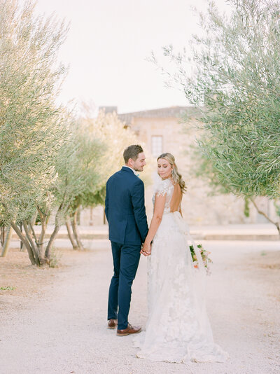 a bride and groom walking away from the camera in an orchard at sunstone winery