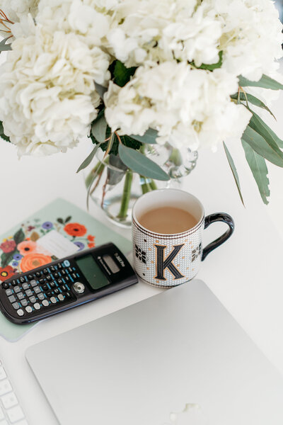 Calculator sitting next to a cup of coffee and a bouquet of flowers