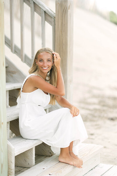 A senior photo of the girl sitting on on the stairs at the beach of the Outer Banks