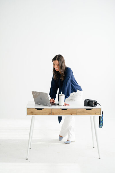 Brand Strategist and Founder of Branding by Jo Standing leaning onto a desk during a brand photo session in Denver.