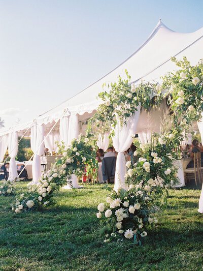 Sailcloth tent with floral installation at an outdoor wedding ceremony,