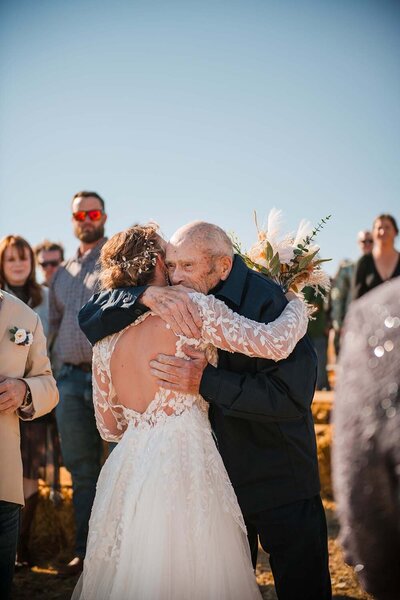 A grandfather embraces his granddaughter at her wedding in western Montana.