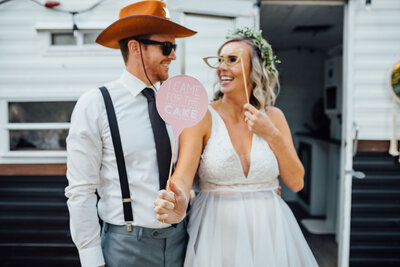 bride and groom smiling in front of photo booth camper