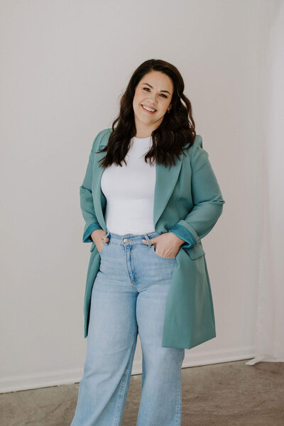 woman with dark hair in teal blazer and jeans smiling at camera