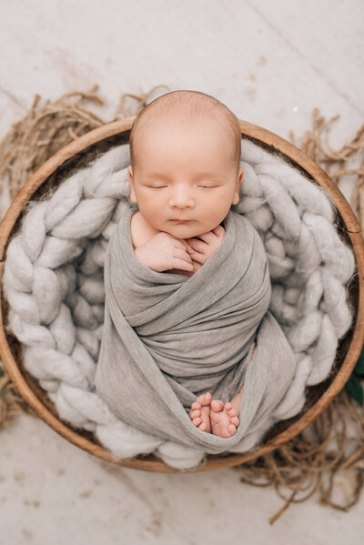 A close-up of a newborn baby boy, wrapped in white at his newborn session with Sharon Leger Photography.