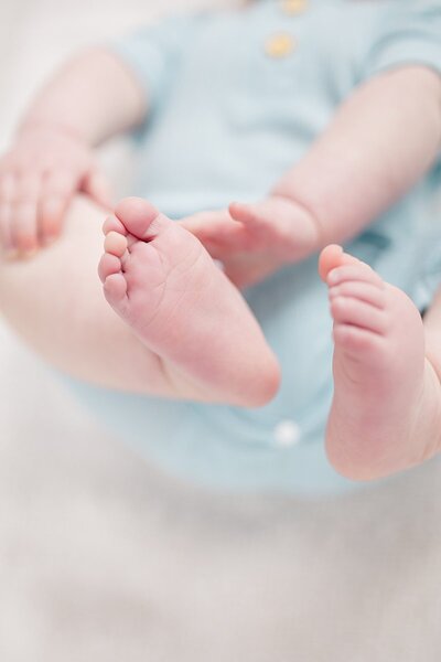Baby in blue onesie with closeup shot of his toes