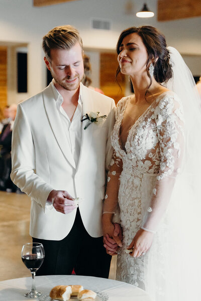 a bride and groom taking communion during their wedding ceremony. The bride is holding back tears.