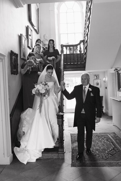 Bride walking downstairs with dad at Iscoyd Park before wedding ceremony