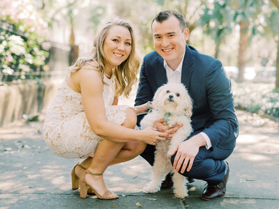 husband and wife posing with their small white dog
