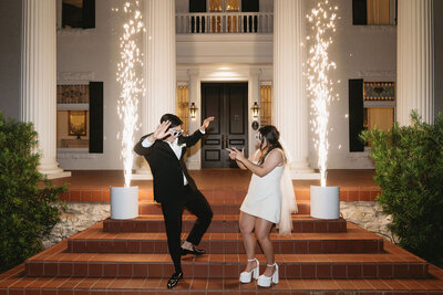 Bride and groom dancing during their wedding grand exit on stairs with cold sparks 