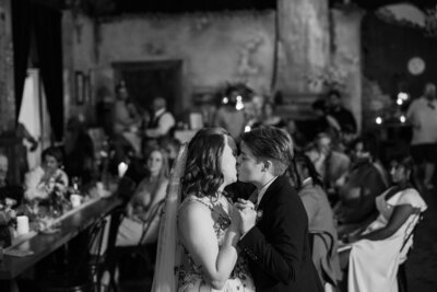Two brides kiss during their first dance in Night Owl Lounge near Boulder, CO. Photo by Claire Katan, at an LGBTQIA+ wedding.