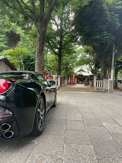 Black Ferrari parked under the illuminated Tokyo Skytree at night, showcasing a luxury night tour experience in Tokyo.