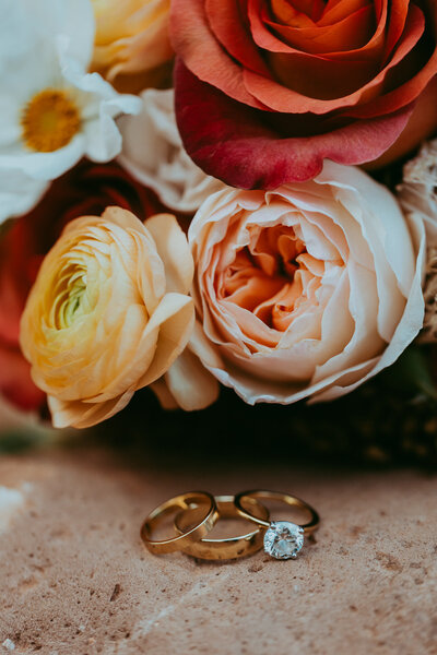 wedding rings on red rocks with bouquet of flowers