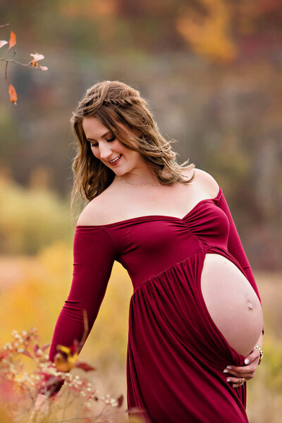 Pregnant mom wearing a red maternity dress for her outdoor maternity photography session in Burlington, Ontario.