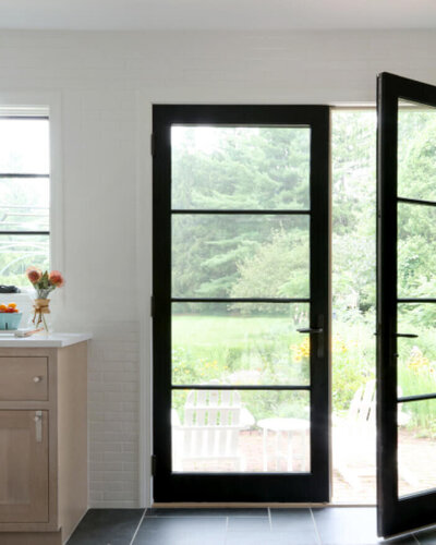 Westwood interior designer installs new black Marvin doors during a kitchen renovation, featuring natural slate flooring and white oak kitchen cabinets.