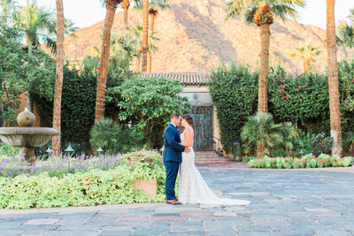 Bride and groom on their wedding day at the Royal Palms Resort and Spa in their wedding attire with the tall palm trees and mountains in the backdrop.