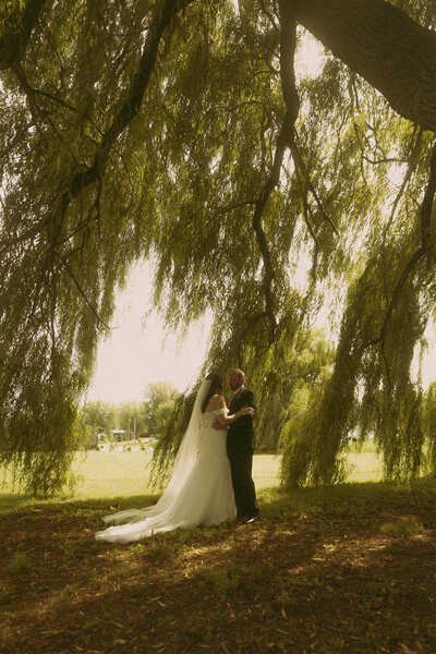 Man and woman romantically spin around, laughing in the middle of a  flowery field
