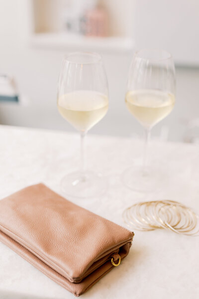 Glasses of wine and a bag on top of a white table