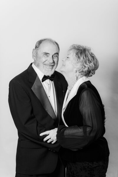 Candid black and white photo of a formally dressed couple sharing a joyful moment during a Vogue Portrait photo booth session in Richmond, VA.