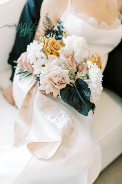bride with bouquet sitting on groom's lap