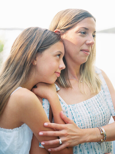Tween daughter rests head on mother's shoulder while gazing lovingly at her, captured on film by Bailey Feeler