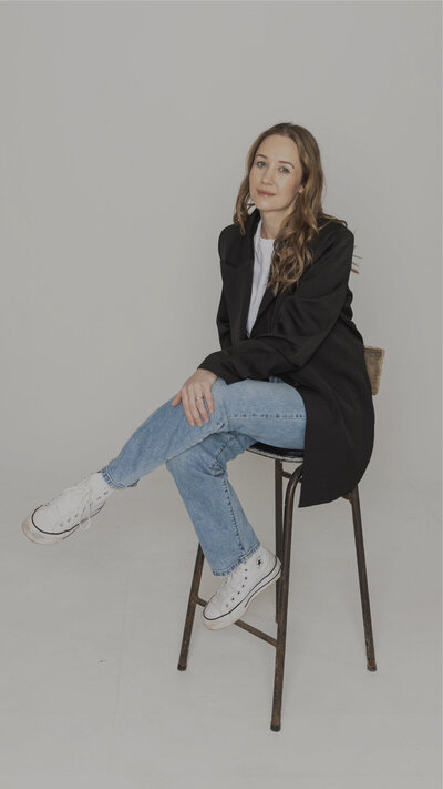 Designer sat on the floor with a cup of tea and laptop smiling