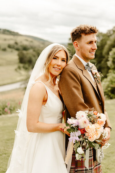 bride wearing white lace dress hugging groom both with huge smiles fun aberdeen wedding photography