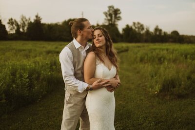 A wedding photograph of a couple in black about to kiss