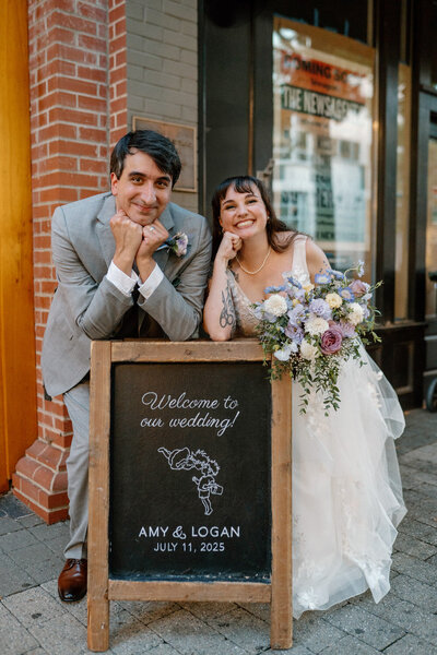 Bride and groom posing with a chalkboard wedding sign