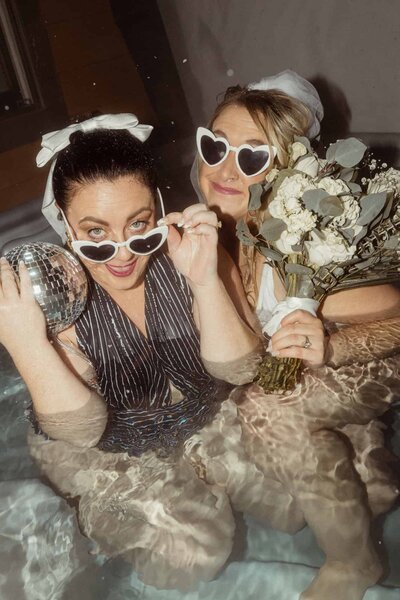 Two brides celebrating their wedding in a hot tub