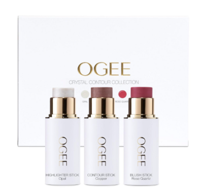 A trio of OGEE crystal contour sticks in sleek white and gold packaging, labeled as highlighter, contour, and blush. Displayed in front of a branded white box, ideal for clean, natural makeup looks.