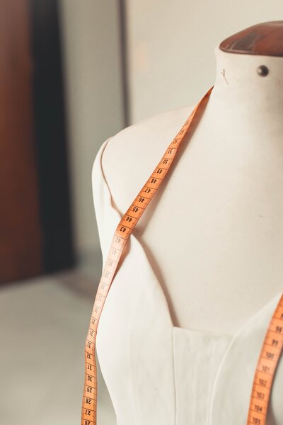 Mannequin in a wedding dress with an orange tape measure.