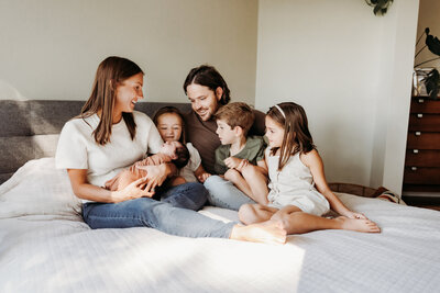 Salem Family Photography Services, family cuddled up in bed around newborn baby