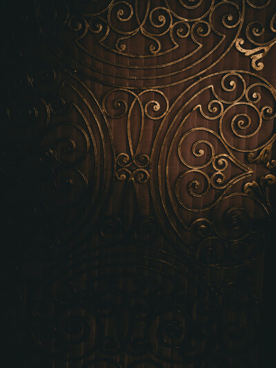 Ornate dark brown swirling pattern with elegant curls and flourishes on a black background creates a luxurious vintage design.