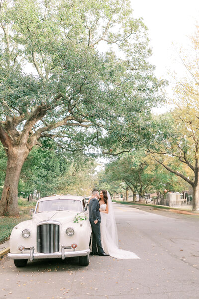Couple posing with vintage white car on wedding day in Savannah