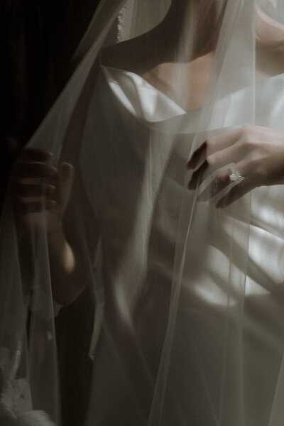Editorial bridal portrait: bride in modern gown plays with sheer veil, flaunting engagement ring — Toronto wedding photo