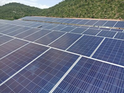 Close-up view of solar panels installed in a rural, hilly landscape, highlighting clean energy solutions in natural environments