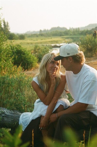 A couple sits on a log and looks at each other in Jackson, Wyoming.