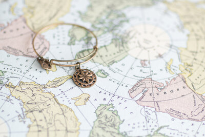 Alex and Ani bracelet laying on a map because Nicole Weeks Photography love to travel to destinations so photograph weddings.