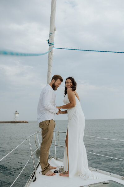 bride and groom standing on a sailboat over lake superior saying vows. photo taken by a Minnesota Elopement Photographer