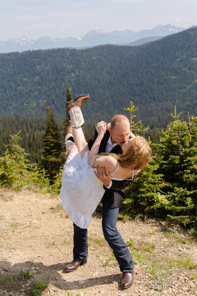 couple laughing and smiling at each other during their adventure session on a mountain top
