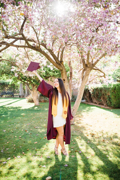 ASU senior graduate holding hat in the air