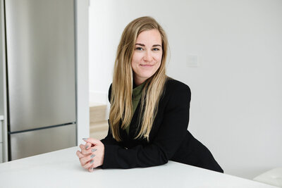 Canadian Realtor Tamara leaning on a kitchen island of a clean white home