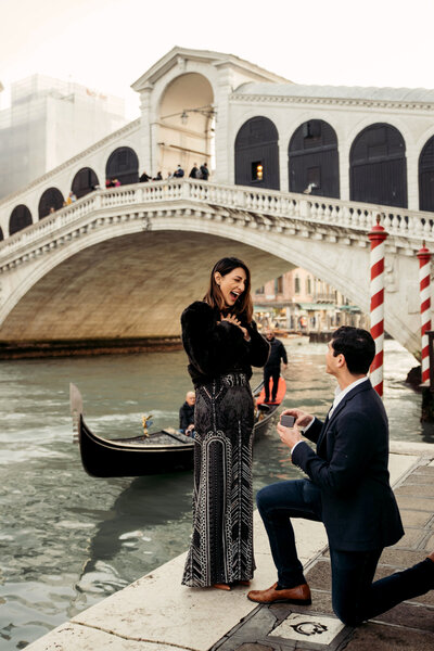 A guy proposes to his girlfriend under Rialto bridge in Venice, Italy while doing a photoshoot with a professional photographer