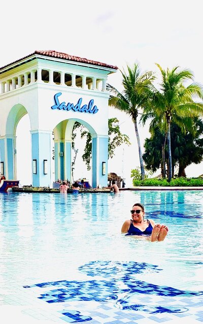 Woman playing in large pool  in Jamaica with swim up pool behind her