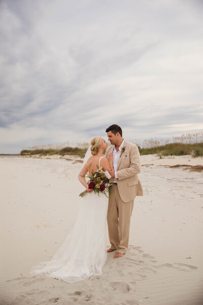 bride and groom hugging on beach after elopement
